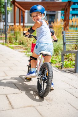 Küçük kız yazın Avrupa 'daki apartmanların avlusunda iki tekerlekli bisiklet sürüyor. Yüksek kalite fotoğraf