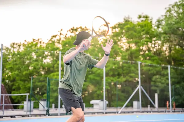 Profesyonel erkek tenisçi gün batımında kortun dışında tenis oynuyor. Yüksek kalite fotoğraf