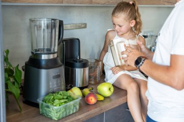 Genç bir babası ve küçük kızı olan bir aile ev mutfağında meyve suyu ya da smoothie hazırlıyor. Yüksek kalite fotoğraf