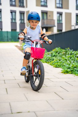 Küçük kız yazın Avrupa 'daki apartmanların avlusunda iki tekerlekli bisiklet sürüyor. Yüksek kalite fotoğraf