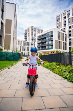 Küçük kız yazın Avrupa 'daki apartmanların avlusunda iki tekerlekli bisiklet sürüyor. Yüksek kalite fotoğraf