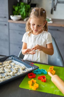 Ev mutfağında hayvan şekilli kesicilerle hamur ile kurabiye yapan küçük bir kız. Aile kavramı. Yüksek kalite fotoğraf