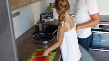 Genç baba ve kızı ev mutfağında birlikte balık pişiriyorlar. Yüksek kalite 4k görüntü