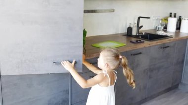 Küçük kız mutfakta buzdolabının kapısını açıyor ve akşam yemeğinde balık yiyor. Yüksek kalite 4k görüntü