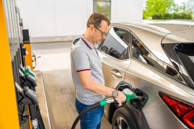 Şoför Avrupa 'daki self servis benzin istasyonunda pahalı benzin dolduruyor. Yüksek kalite fotoğraf