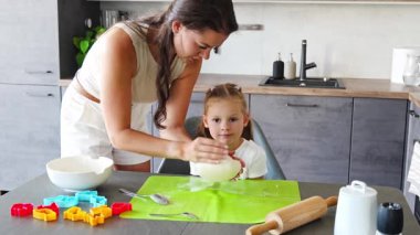 Genç anne ve kızı mutfakta kurabiye için para kazanıyorlar. Ev mutfağında mutlu bir aile. Yüksek kalite 4k görüntü