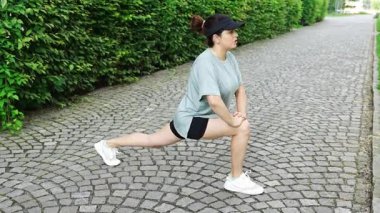 Spor giyimli genç bir kadın şehir caddesinde egzersiz yapıyor. Koşmadan ya da koşmadan önce ısın. Açık hava sporları eğitimi konsepti. Yüksek kalite 4k görüntü