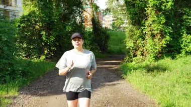 Yaz parkında genç bayan koşucu eğitimi. Spor salonundaki kadın dışarıda koşuyor. Sabah koşusu kavramı. Yüksek kalite 4k görüntü