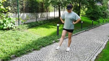 Şehir parkında ayak ve bacak egzersizi yapan genç bir kadının yakın çekim görüntüsü. Koşmadan ya da koşmadan önce ısın. Açık hava sporları eğitimi konsepti. Yüksek kalite 4k görüntü
