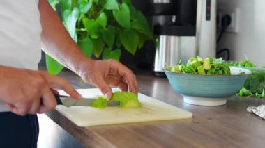 Erkek eller ev mutfağında taze salata için avokado kesiyor. Yüksek kalite 4k görüntü