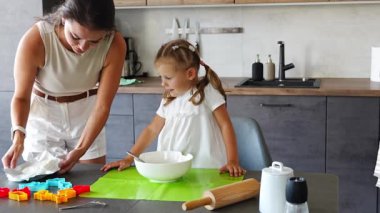 Genç anne ve kızı mutfakta kurabiye için para kazanıyorlar. Ev mutfağında mutlu bir aile. Yüksek kalite 4k görüntü