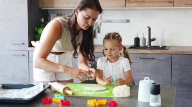 Genç anne ve kızı mutfakta kurabiye için para kazanıyorlar. Ev mutfağında mutlu bir aile. Yüksek kalite 4k görüntü