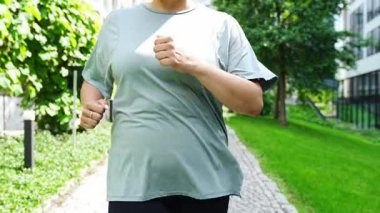 Yaz parkında parkta canlı yürüyüş yapan genç bir kadın. Spor salonundaki kadın dışarıda koşuyor. Sabah koşusu kavramı. Yüksek kalite 4k görüntü
