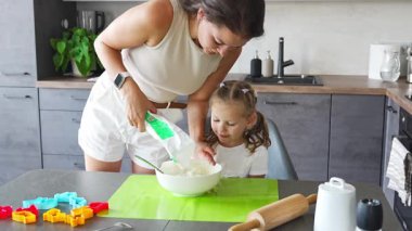 Genç anne ve kızı mutfakta kurabiye için para kazanıyorlar. Ev mutfağında mutlu bir aile. Yüksek kalite 4k görüntü