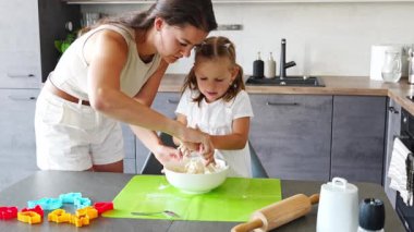Genç anne ve kızı mutfakta kurabiye için para kazanıyorlar. Ev mutfağında mutlu bir aile. Yüksek kalite 4k görüntü