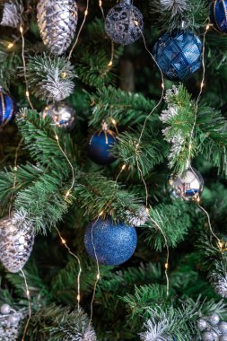 Mavi ve gümüş oyuncaklı Noel ağacı. Şenlikli Noel ağacı çelenklerle süslenmiş. Yeni yılın moda renklerinde sembolü. Yüksek kalite fotoğraf