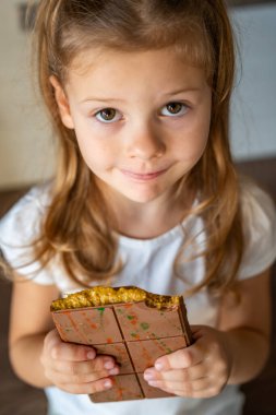 Fıstık ezmeli Dubai çikolatası ve küçük bir kızın elinde kataifi hamuru. Evde, mutfakta el yapımı şekerlemeler var. Yüksek kalite fotoğraf