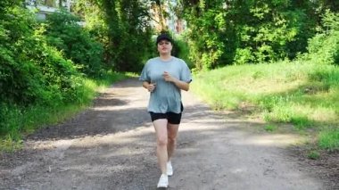 Yaz parkında genç bayan koşucu eğitimi. Spor salonundaki kadın dışarıda koşuyor. Sabah koşusu kavramı. Yüksek kalite 4k görüntü