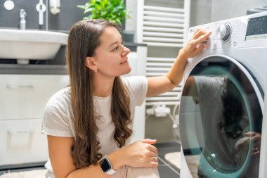 Çamaşır makinesinin kontrol panelinin çamaşır parametrelerini ayarlayan genç bir kadın. Yüksek kalite fotoğraf