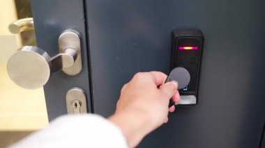 Evin duvarına monte edilmiş bir giriş sistemi okuyucusuyla bir binaya girmek için elektrikli kilit anahtarı kullanan birini kapat. Yüksek kalite 4k görüntü