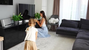 Küçük kız elektrikli süpürgeyle evi temizliyor. Annem ev işleri ve ev işleri için ev işlerini öğretiyor. Yüksek kalite 4k görüntü