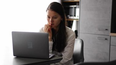 Düşünceli, gergin bir kadın dizüstü bilgisayarda çalışıyor. Ekran başında düşünüyor. Düşünce problemini ev ofisinde çözüyor. 4k görüntü