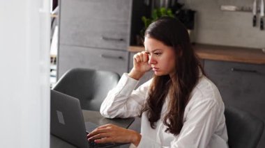 Düşünceli, yorgun bir kadın dizüstü bilgisayarda çalışıyor. Ekran başında düşünüyor. Düşünce problemini ev ofisinde çözüyor. 4k görüntü