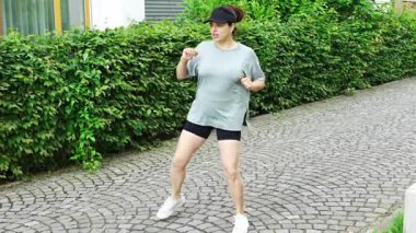 Spor giyimli genç bir kadın şehir caddesinde egzersiz yapıyor. Koşmadan ya da koşmadan önce ısın. Açık hava sporları eğitimi konsepti. Yüksek kalite 4k görüntü