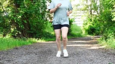Yaz parkında genç bayan koşucu eğitimi. Spor salonundaki kadın dışarıda koşuyor. Sabah koşusu kavramı. Yüksek kalite 4k görüntü