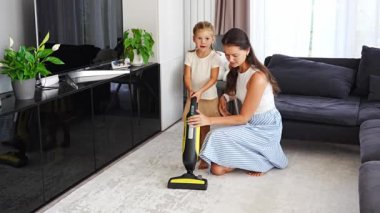 Küçük kızıyla birlikte evi temizleyen genç bir anne. Anne, kız çocuğuna temizlik işleri ve ev işleri için kirli yerleri süpürmeyi öğretiyor. Yüksek kalite 4k görüntü