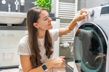 Çamaşır makinesinin kontrol panelinin çamaşır parametrelerini ayarlayan genç bir kadın. Yüksek kalite fotoğraf