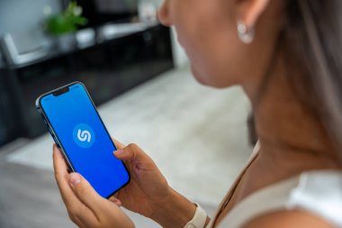 Prag, Çek Cumhuriyeti - 2 Mayıs 2024: Mobil uygulama uygulamasıyla ekranda Shazam uygulamasının logosu olan iPhone 'u tutan kadın. Yüksek kalite fotoğraf