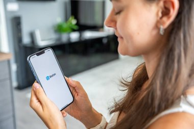 Prag, Çek Cumhuriyeti - 2 Mayıs 2024: Botim uygulamasının logosu olan iPhone 'u ekranda tutan kadın, iş yeri için mobil uygulama kullanıyor. Yüksek kalite fotoğraf