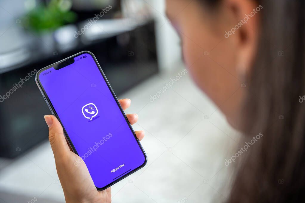 Prague, Czech republic - May 2, 2024: Woman holding iPhone with logo of application Rakuten Viber on the screen, using mobile application for business home. High quality photo
