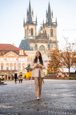 Prag, Çek Cumhuriyeti - 4 Aralık 2024: Çek Cumhuriyeti 'nin Prag kentindeki Old Town Square' de Noel tatilinde Tyn tapınağı ve Noel ağacının yanındaki genç kadın. Yüksek kalite fotoğraf
