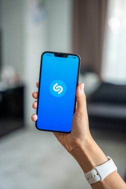 Prag, Çek Cumhuriyeti - 2 Mayıs 2024: Mobil uygulama uygulamasıyla ekranda Shazam uygulamasının logosu olan iPhone 'u tutan kadın. Yüksek kalite fotoğraf