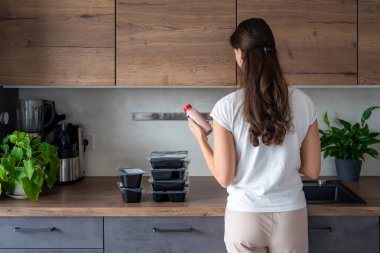 Kilo kaybı için sağlıklı beslenme planı olan genç bir kadın, günlük hazır yemek menüsü teslimatı. Telefonda yemek izleme uygulaması kullanan bir kadın. Tabakla dengeli porsiyon. Pişirme öncesi. Yüksek kalite fotoğraf