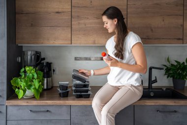 Kilo kaybı için sağlıklı beslenme planı olan genç bir kadın, günlük hazır yemek menüsü teslimatı. Cep telefonu uygulaması ile sipariş edilen yemek. Tabakla dengeli porsiyon. Pişirme öncesi. Yüksek kalite fotoğraf