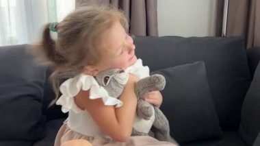 Evdeki kanepede otururken en sevdiği peluş tavşanına sarılan küçük kız. Yüksek kalite 4k görüntü