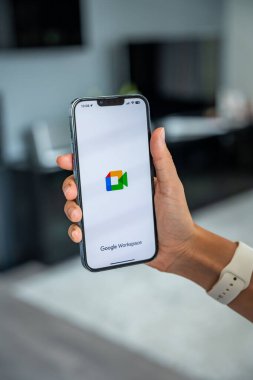 Prag, Çek Cumhuriyeti - 2 Mayıs 2024: Goole Meet uygulamasının logosuyla iPhone 'u elinde tutan kadın, iş yeri için mobil uygulama kullanıyor. Yüksek kalite fotoğraf