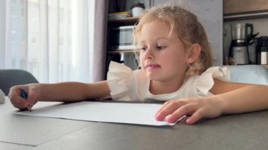 Evde masada oturan kalemlerle resim yapan küçük bir kız. Yüksek kalite 4k görüntü