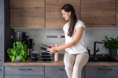 Kilo kaybı için sağlıklı beslenme planı olan genç bir kadın, günlük hazır yemek menüsü teslimatı. Cep telefonu uygulaması ile sipariş edilen yemek. Tabakla dengeli porsiyon. Pişirme öncesi. Yüksek kalite fotoğraf
