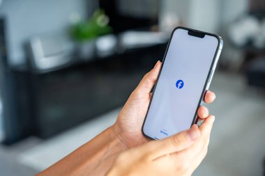 Prag, Çek Cumhuriyeti - 2 Mayıs 2024: İş yeri için mobil uygulama kullanan, ekranda Meta Facebook uygulaması logosu olan iPhone 'u tutan kadın. Yüksek kalite fotoğraf