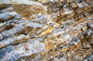 Karadağ 'ın Budva kentindeki katmanlı kaya dokusu. Gri ve kahverengi engebeli tortulu kayalar. Katmanların ve çatlakların doğal oluşumu, jeolojik yapı. Yüksek kalite fotoğraf