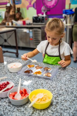 Yemek kursunda yemek yapmayı öğrenen küçük bir kız. El yapımı tatlı. Çikolatalı şeker yapmak, çocuk kalp şeklindeki kalıbı çikolatayla doldurmak. Yüksek kalite fotoğraf