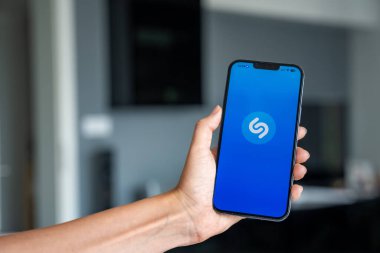 Prag, Çek Cumhuriyeti - 2 Mayıs 2024: Mobil uygulama uygulamasıyla ekranda Shazam uygulamasının logosu olan iPhone 'u tutan kadın. Yüksek kalite fotoğraf
