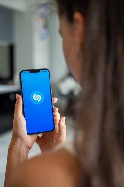 Prag, Çek Cumhuriyeti - 2 Mayıs 2024: Mobil uygulama uygulamasıyla ekranda Shazam uygulamasının logosu olan iPhone 'u tutan kadın. Yüksek kalite fotoğraf