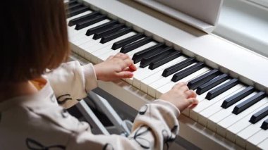 Beyaz piyano sentezleyicili kız için ev müziği dersi. Erken gelişim kavramı: müzik öğrenmek motor becerileri, işitme ve zekayı geliştirir, çocukluktan itibaren yaratıcılığı teşvik eder.. 