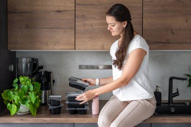 Kilo kaybı için sağlıklı beslenme planı olan genç bir kadın, günlük hazır yemek menüsü teslimatı. Cep telefonu uygulaması ile sipariş edilen yemek. Tabakla dengeli porsiyon. Pişirme öncesi. Yüksek kalite fotoğraf