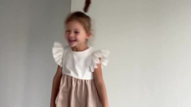 Küçük kız yatakta zıplıyor, eğleniyor. Çocuk neşeli bir ruh hali içinde evde hafta sonunun tadını çıkarıyor. Yüksek kalite 4k görüntü